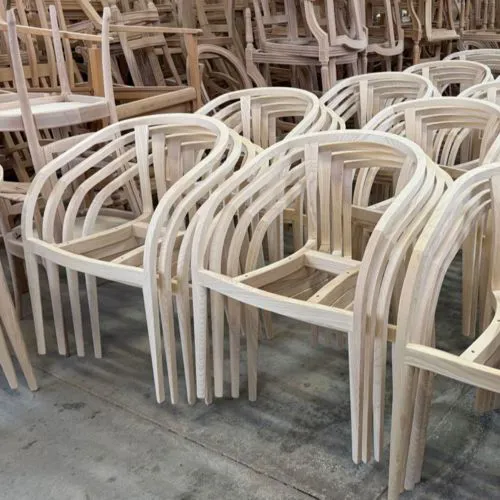 Artigiano al lavoro sulla struttura in legno di una sedia, fase di produzione nel laboratorio.